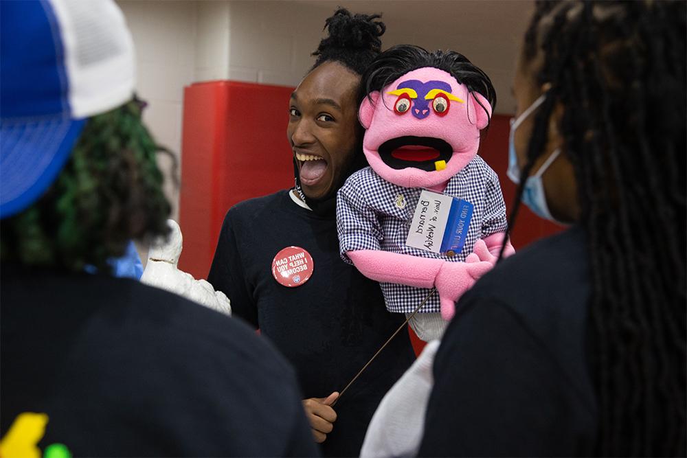 student holding puppet with a button saying "what can I help you become?"