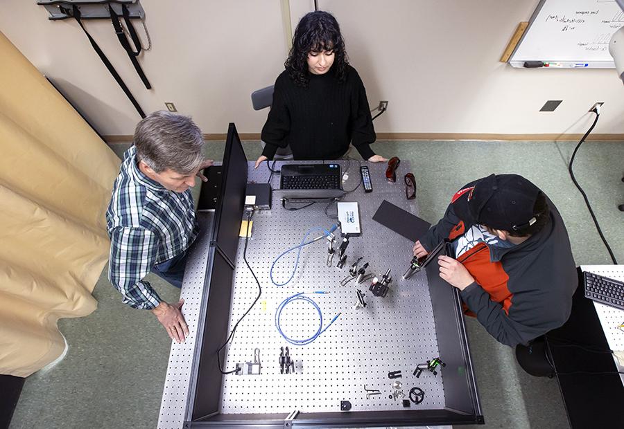 Students working in the physics lab with faculty member