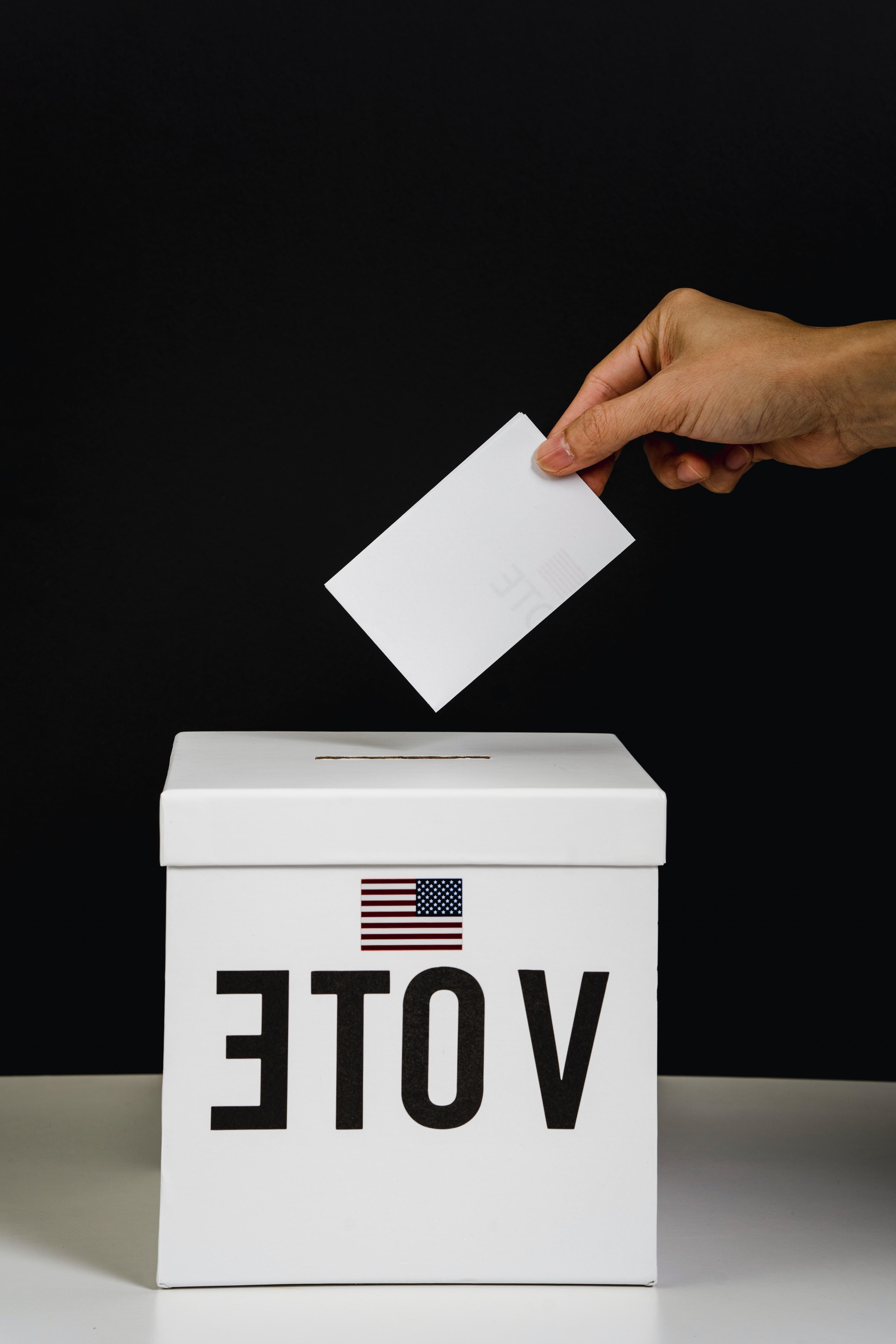 A person putting paper in a voting box